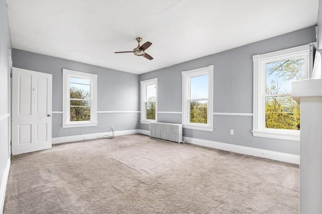 unfurnished bedroom featuring carpet, baseboards, radiator, and ceiling fan