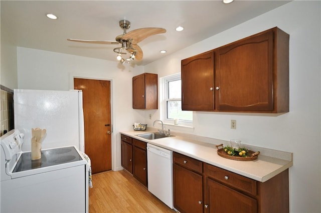 kitchen featuring a sink, light countertops, light wood-type flooring, and white appliances