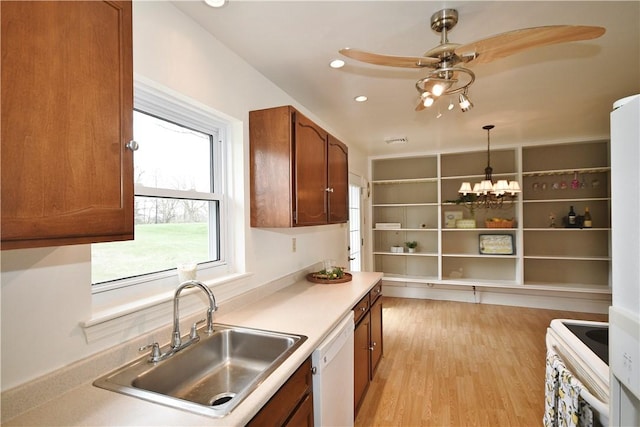 kitchen with white appliances, decorative light fixtures, light wood finished floors, ceiling fan with notable chandelier, and a sink