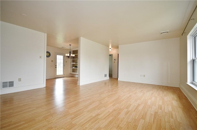 unfurnished living room featuring a notable chandelier, visible vents, light wood-type flooring, and baseboards