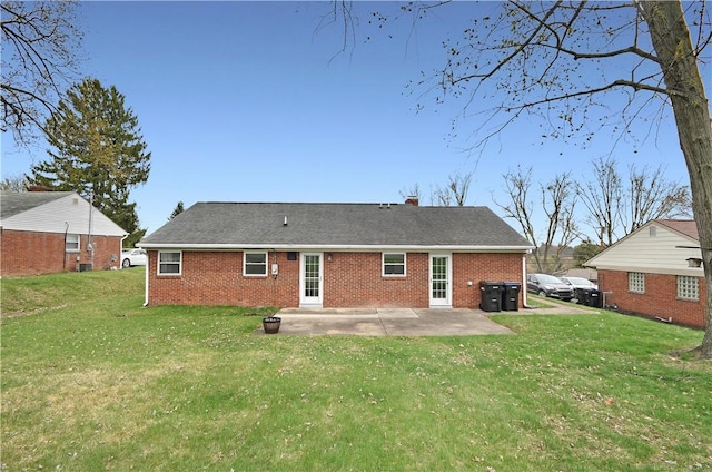 back of house featuring a patio area, brick siding, and a yard