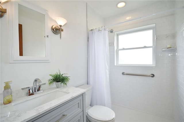 bathroom with vanity, a tile shower, and toilet