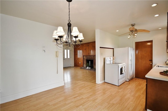 kitchen with light wood-style floors, ceiling fan with notable chandelier, white appliances, light countertops, and a sink