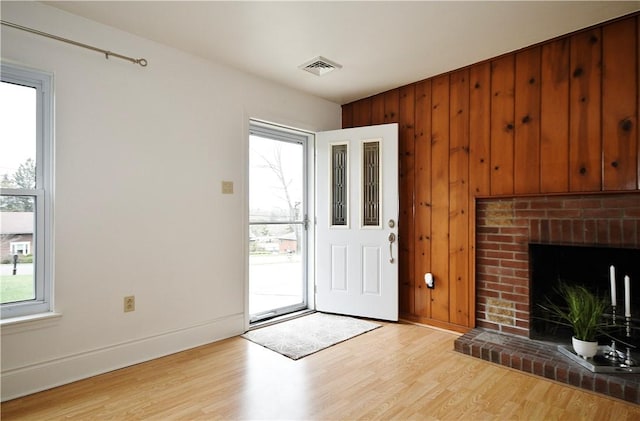 foyer with wooden walls, light wood-style flooring, and baseboards