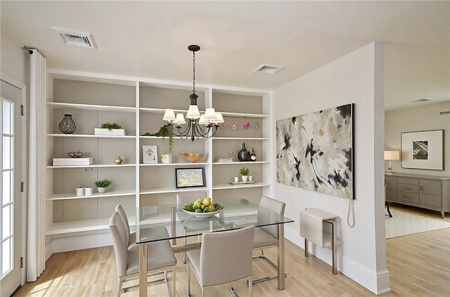 dining space with visible vents, an inviting chandelier, and wood finished floors