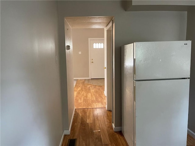 corridor with visible vents, baseboards, and wood finished floors
