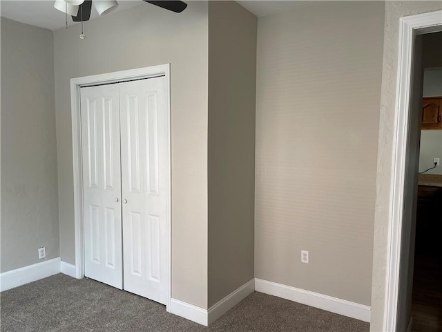 unfurnished bedroom featuring dark carpet, a closet, baseboards, and a ceiling fan