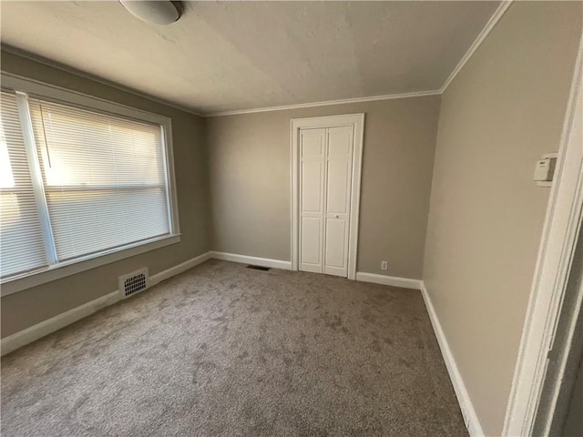 unfurnished bedroom with ornamental molding, visible vents, a closet, and carpet