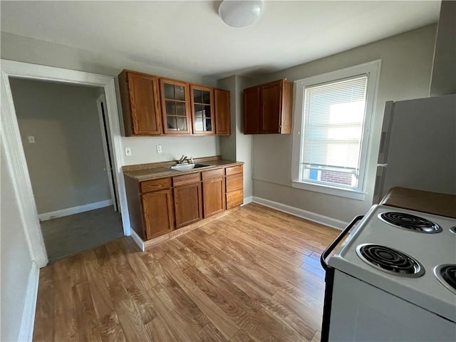 kitchen featuring white appliances, brown cabinets, baseboards, and light wood finished floors