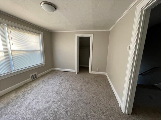 unfurnished bedroom with ornamental molding, a closet, carpet, and visible vents