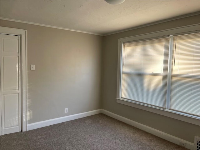 carpeted empty room featuring ornamental molding and baseboards