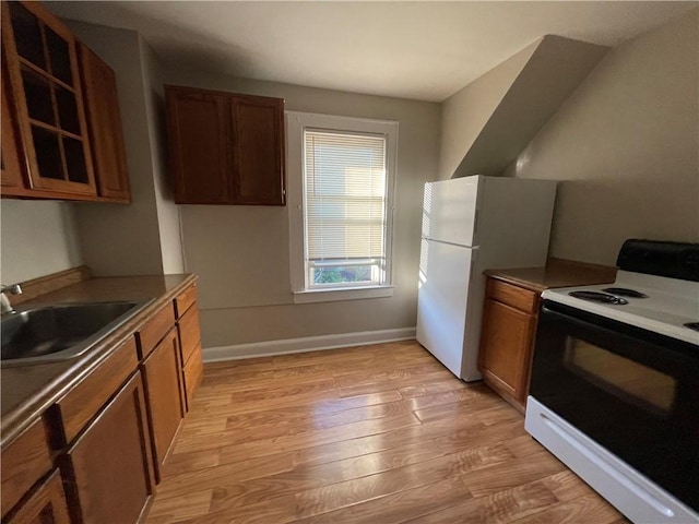 kitchen featuring freestanding refrigerator, a sink, range with electric cooktop, brown cabinets, and light wood finished floors