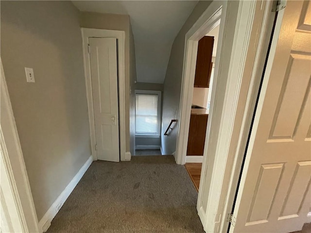 hallway with dark colored carpet and baseboards