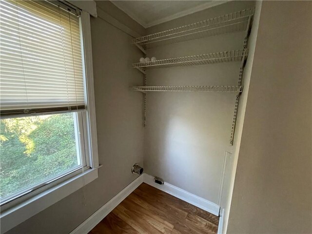 clothes washing area featuring baseboards, laundry area, ornamental molding, and wood finished floors