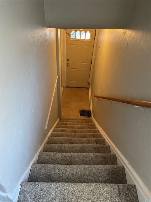 stairs featuring tile patterned flooring and visible vents