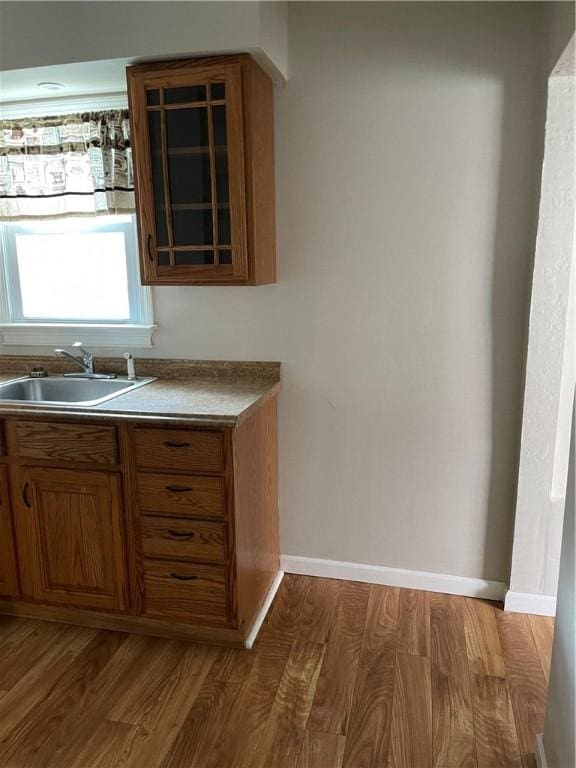 bar featuring wood finished floors, a sink, and baseboards