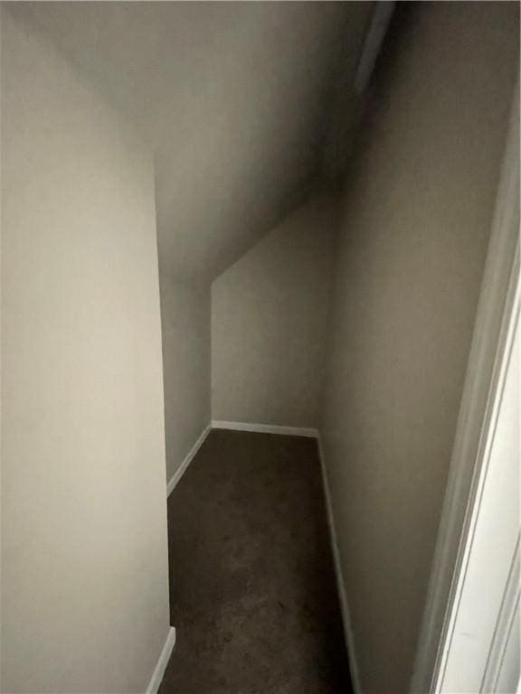 bonus room with dark colored carpet, baseboards, and lofted ceiling