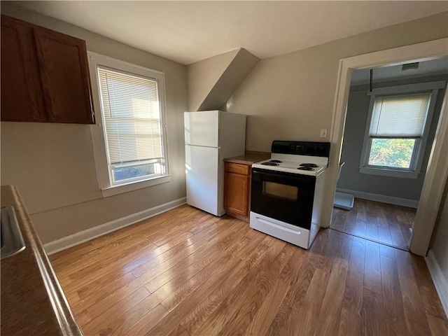 kitchen featuring baseboards, freestanding refrigerator, brown cabinets, light wood finished floors, and electric range oven