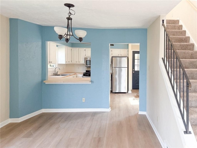 1138 Oakmont Ave, Oakmont, PA 15139 - kitchen with range with gas cooktop, a sink, freestanding refrigerator, white cabinetry, and light wood-style flooring