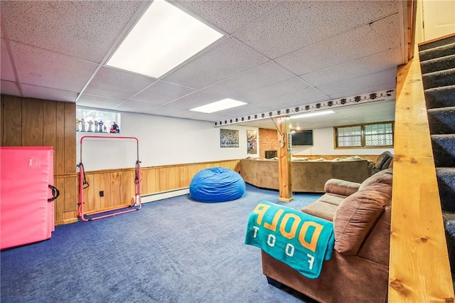 game room with a baseboard radiator, a paneled ceiling, wooden walls, and carpet floors