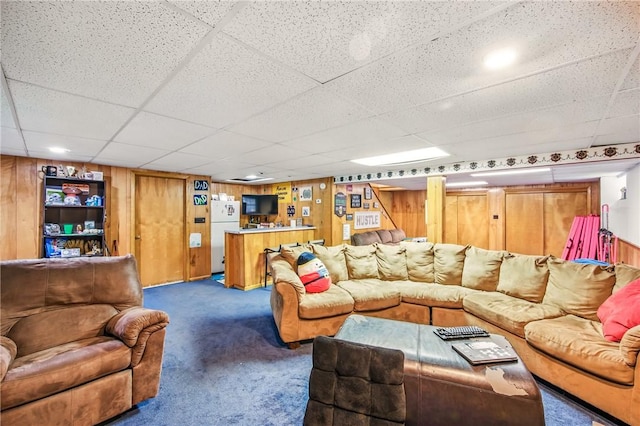 living room with wooden walls, a paneled ceiling, and carpet flooring