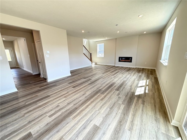 406 Barons Ct, Peters Twp, PA 15367 - unfurnished living room featuring wood finished floors, recessed lighting, stairway, baseboards, and a glass covered fireplace