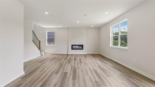 406 Barons Ct, Peters Twp, PA 15367 - unfurnished living room with light wood-type flooring, a glass covered fireplace, recessed lighting, and stairs