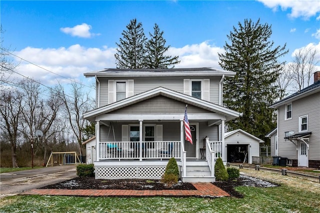 american foursquare style home with concrete driveway, a detached garage, an outbuilding, and covered porch