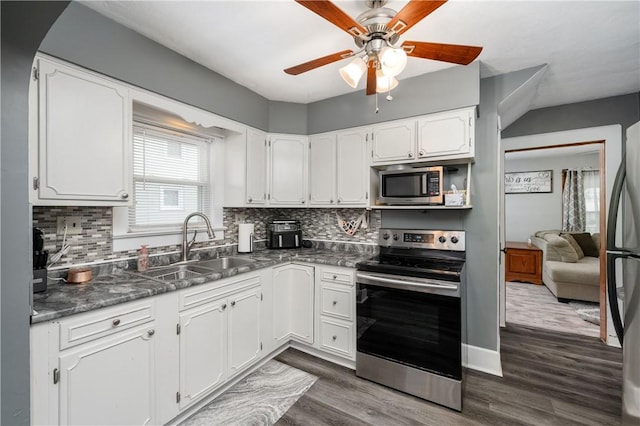 kitchen with white cabinetry, a ceiling fan, dark countertops, a sink, and stainless steel appliances