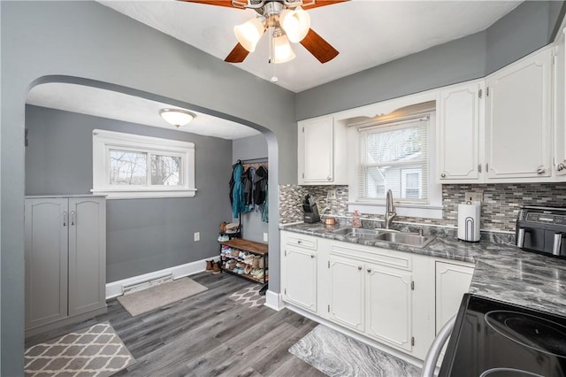 kitchen with black electric range, arched walkways, a sink, and a healthy amount of sunlight
