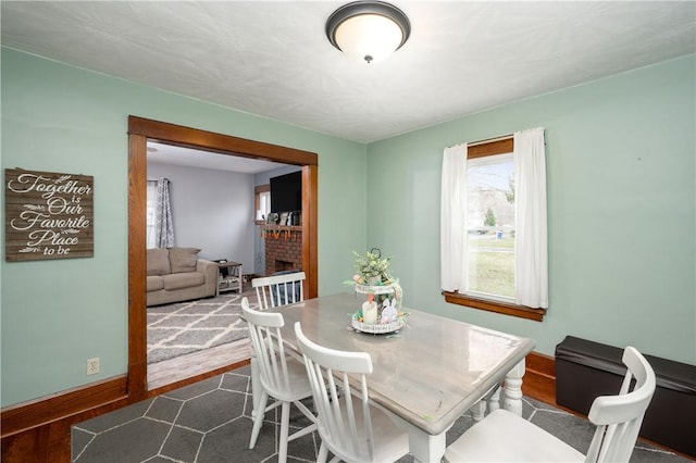 dining room with baseboards, a fireplace, and dark wood finished floors