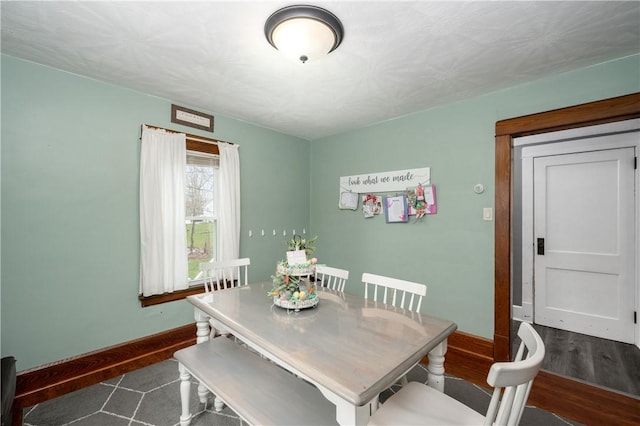 dining area with baseboards and dark wood finished floors