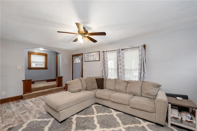 living area featuring baseboards, a ceiling fan, arched walkways, and wood finished floors