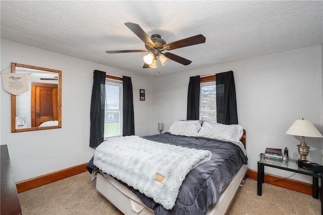 carpeted bedroom featuring ceiling fan, multiple windows, baseboards, and a textured ceiling