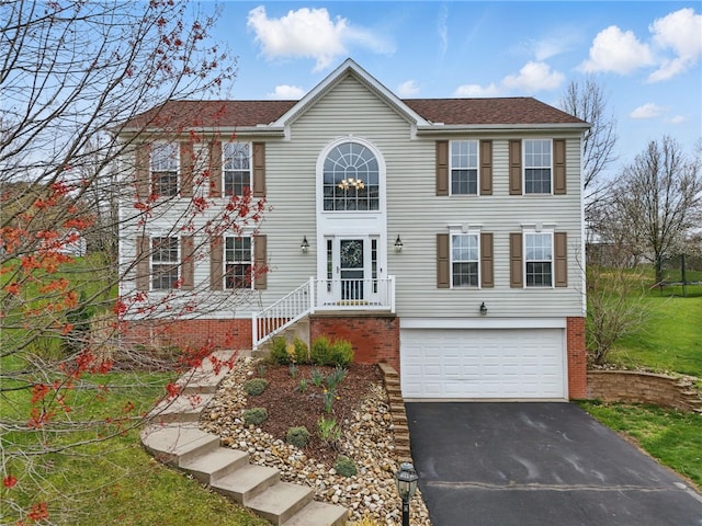 colonial home with an attached garage, roof with shingles, and driveway