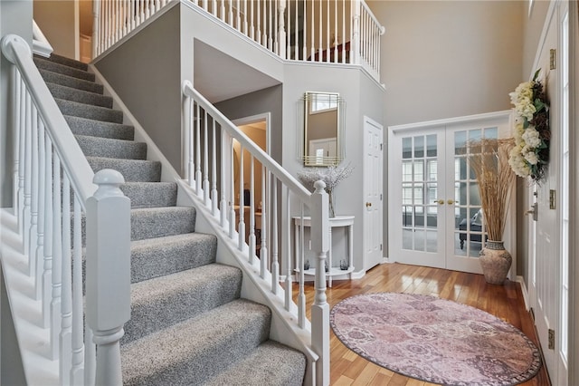 entryway with a towering ceiling, baseboards, french doors, stairs, and hardwood / wood-style floors