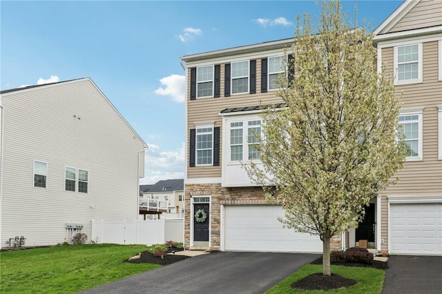 view of property with aphalt driveway, a front yard, fence, stone siding, and an attached garage