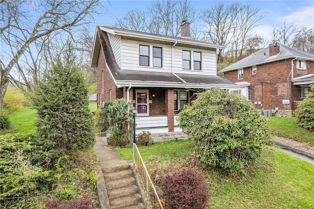 view of front of property featuring a porch, a chimney, stairway, and brick siding
