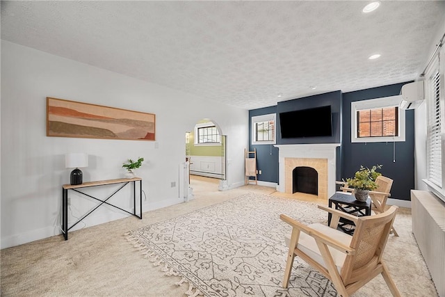 living area featuring baseboards, arched walkways, a tiled fireplace, recessed lighting, and light carpet