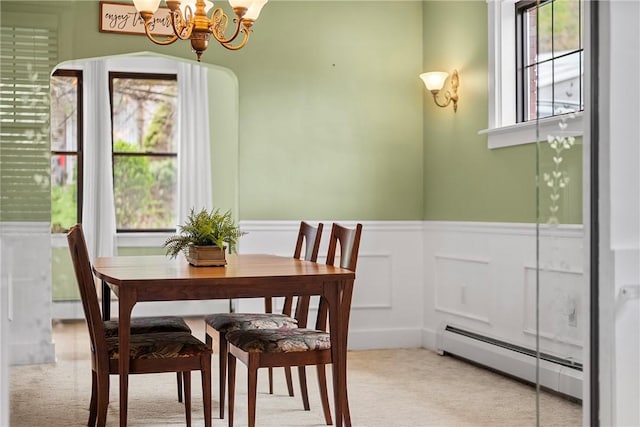 dining room featuring light carpet, a notable chandelier, a baseboard radiator, and wainscoting