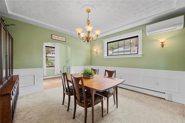 dining room featuring a wall mounted air conditioner, wainscoting, a baseboard radiator, and a textured ceiling