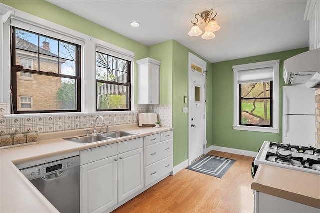 kitchen featuring stainless steel dishwasher, freestanding refrigerator, light wood-style flooring, white cabinetry, and a sink