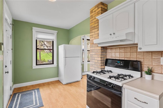 kitchen with under cabinet range hood, freestanding refrigerator, range with gas cooktop, and white cabinets