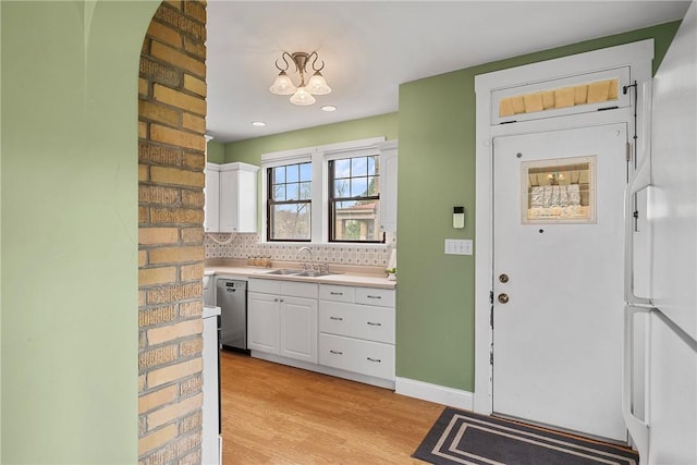 kitchen with light wood-style flooring, dishwasher, a sink, and white cabinets