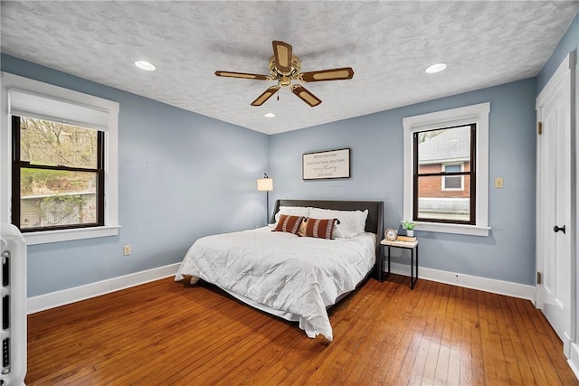 bedroom featuring recessed lighting, wood-type flooring, baseboards, and a ceiling fan