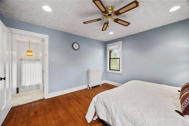 bedroom featuring baseboards, a ceiling fan, hardwood / wood-style flooring, recessed lighting, and radiator heating unit