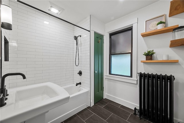 bathroom featuring baseboards,  shower combination, visible vents, radiator, and a sink