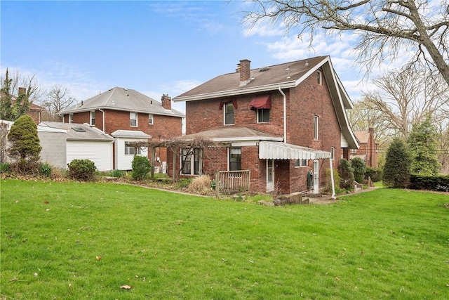 rear view of house with a chimney, a yard, and brick siding