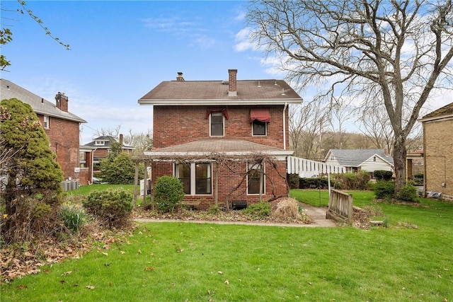 back of house with a chimney, a lawn, and brick siding