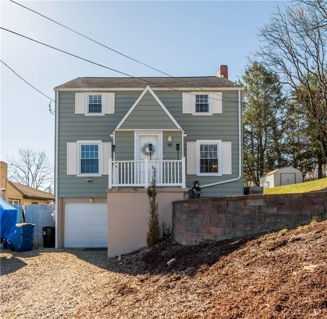 view of front facade featuring an attached garage, a chimney, driveway, and fence